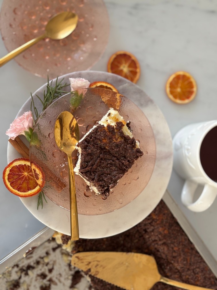 Sernik królewski podany na talerzu wokół którego leżą kawałki pomarańczy